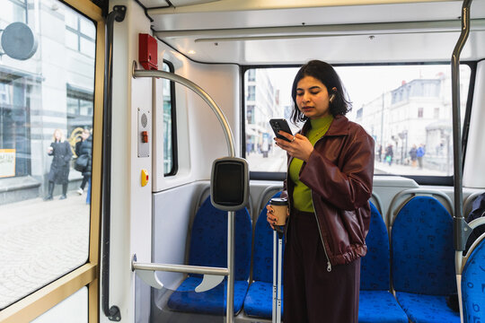 Young woman using phone while commuting on a modern city tram