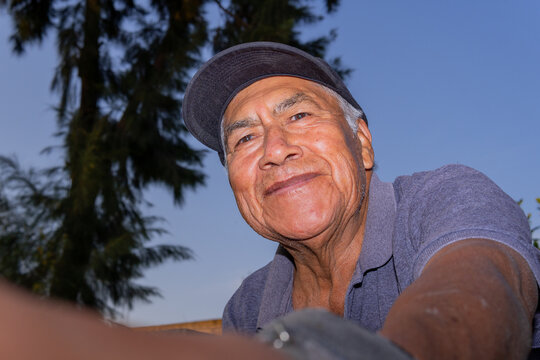 Smiling older hispanic farm worker looking up