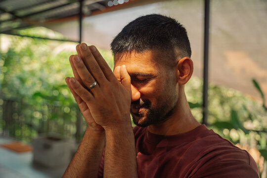 Man With Hands Together Smiling in a Sunny Indoor Space