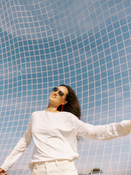 Woman Enjoys Sunny Day Under Net at Sports Field