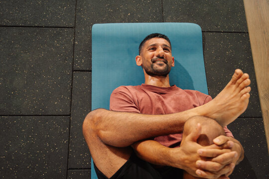 Man Doing Yoga on Mat in Indoor Gym During Daytime