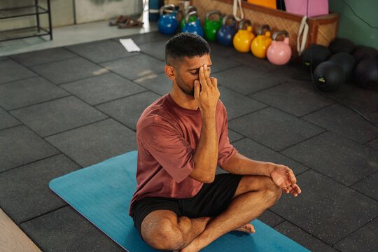 Man Practices Breathing Exercises Indoors in a Fitness Studio