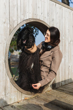 Woman and her Afghan Hound posing through a circular wooden window