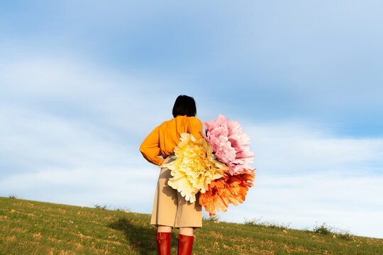 Woman stands in a field with large colorful flowers during spring