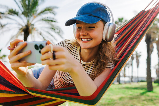 Person relaxing in hammock watching smartphone video