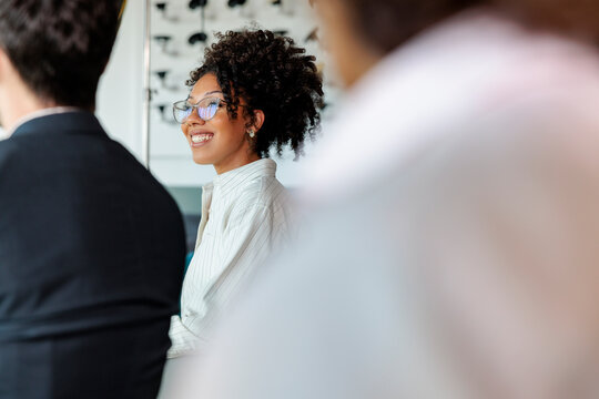 Smiling woman listening during meeting with colleagues in office