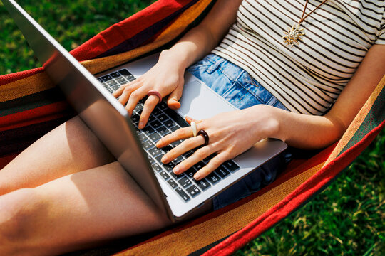 Person typing on laptop in colorful outdoor hammock