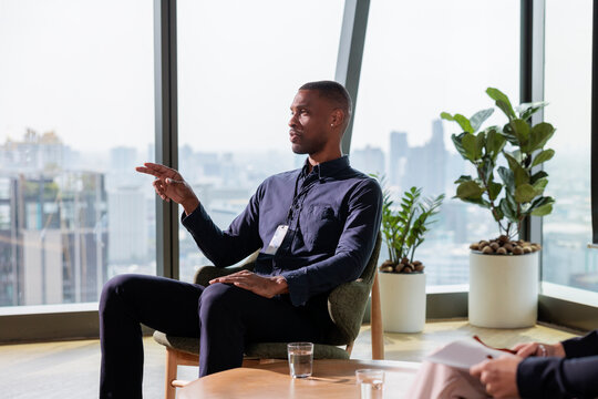 Man in meeting points to city skyline view.