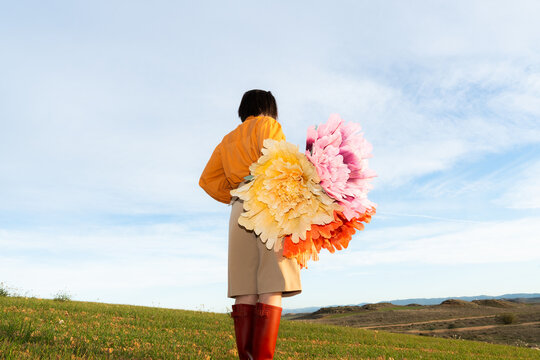 Woman stands in a field with large colorful flowers during spring
