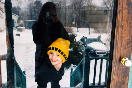 Cute candid portrait of happy child looking outside after snowstorm