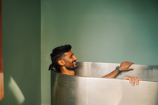 Man Enjoying Ice Bath in a Metal Bathtub in a Simple Room Setting