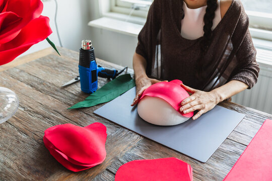 Woman making a giant red paper rose for event decoration