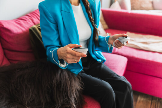 Woman using a VR headset on a pink sofa next to her sleeping dog