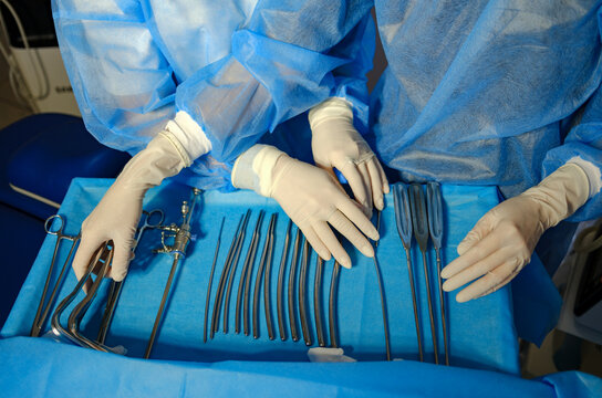 hands of an intern and a doctor near instruments on a table