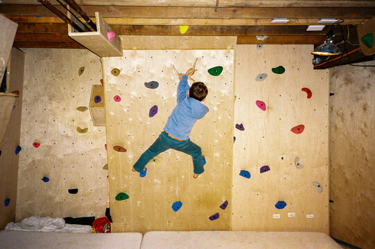 Child climbing on a DIY basement climbing wall at home