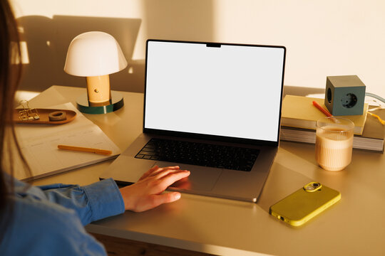 Woman hand using laptop with white screen mockup at home office desk