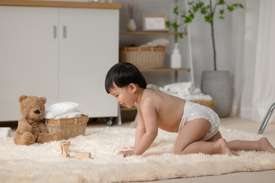 Adorable baby boy crawling on a fluffy rug with toys and a teddy