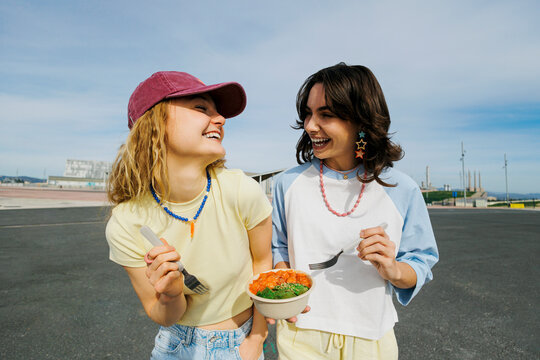 Smiling friends enjoying healthy poke bowls outdoors