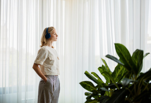 Woman Relaxing at Home With Headphones and Plants