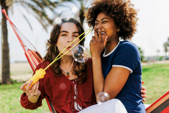 Diverse friends enjoying summer leisure blowing bubbles together