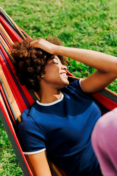 Person relaxing in hammock enjoying summer sunlight
