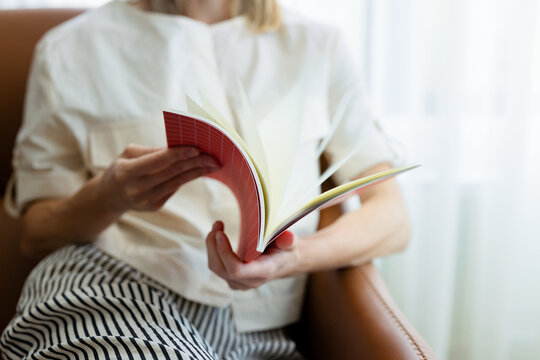 Woman Reading From a Notebook in a Comfortable Armchair