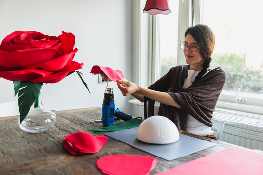 Woman making a giant red paper rose for event decoration