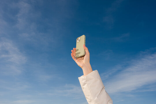 Holding a Phone up to the Blue Sky 