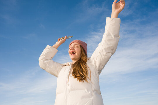 Woman Enjoys Time With Cellphone Under Blue Sky