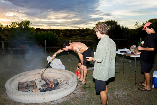 UGC Young men friends gathering around campfire in NSW Australia