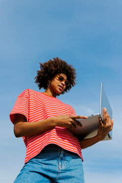 Person working outdoors with laptop under sky