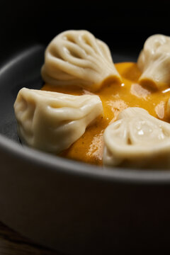 Georgian khinkali dumplings served with sauce in ceramic bowl