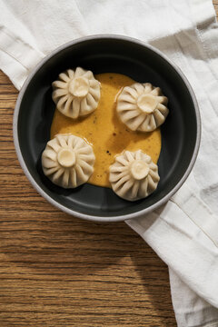 Georgian khinkali dumplings served with sauce in ceramic bowl