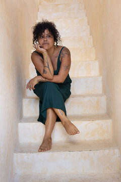 pensive woman sitting portrait with tattoos and long dress