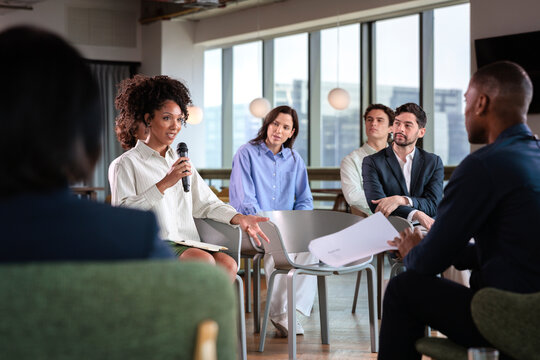 Businesswoman speaks at meeting with diverse colleagues.