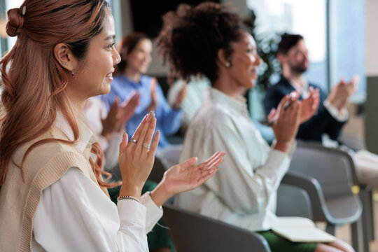 Diverse audience applauds at a conference or presentation.