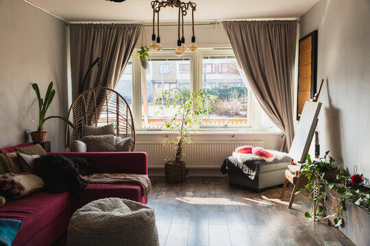 Bright and stylish bohemian living room with a hanging chair and pink