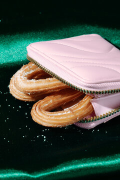 close view of churros inside a pink purse on green satin
