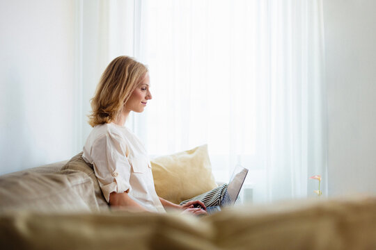 Woman Working On Laptop At Home On Sofa