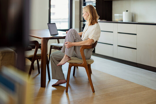 Woman Working Remotely on Laptop in Kitchen