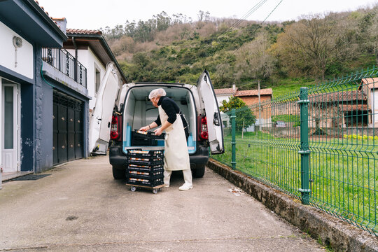 Artisan cheesemaker loading cheese products into delivery van