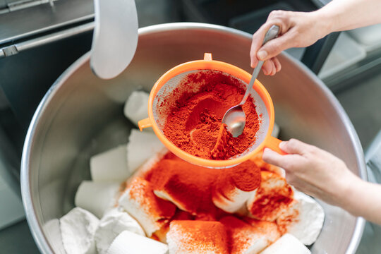 Artisan cheesemaker adding paprika to fresh cheese