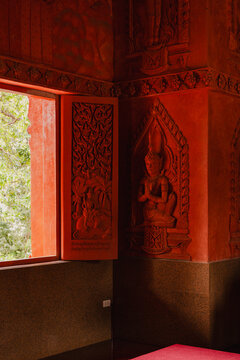 Carved walls and window in a red-painted temple room 