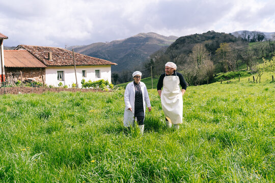 Artisan cheesemakers walking across green field near rural factory