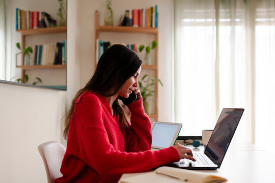 Composed Woman Multitasking on Phone and Laptop