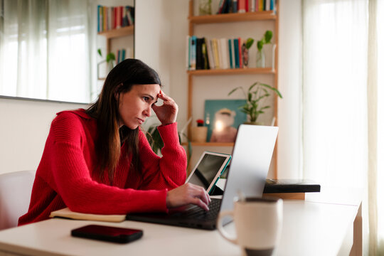 Worried woman using laptop at home office