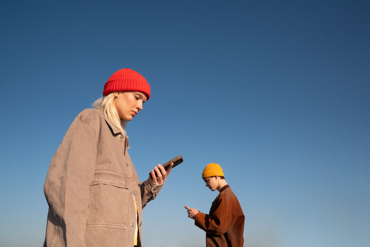 Young People Using Smartphones Against Blue Sky 