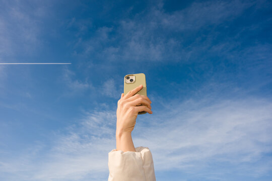 Person Hand Holds Phone Under Clear Blue Sky