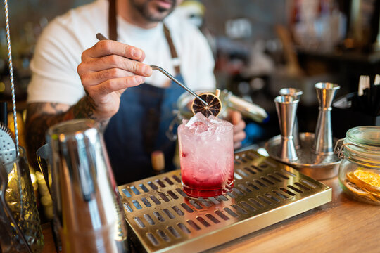 Bartender garnishing craft cocktail with dried orange slice