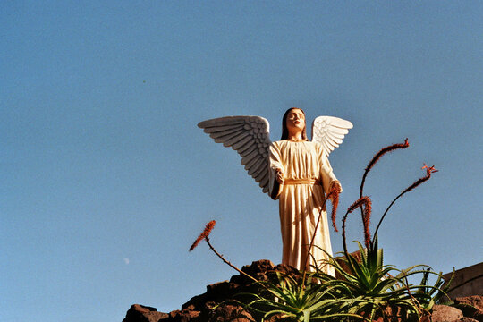 Angel Statue Above Volcanic Rocks in Madeira Under Clear Blue Sky
